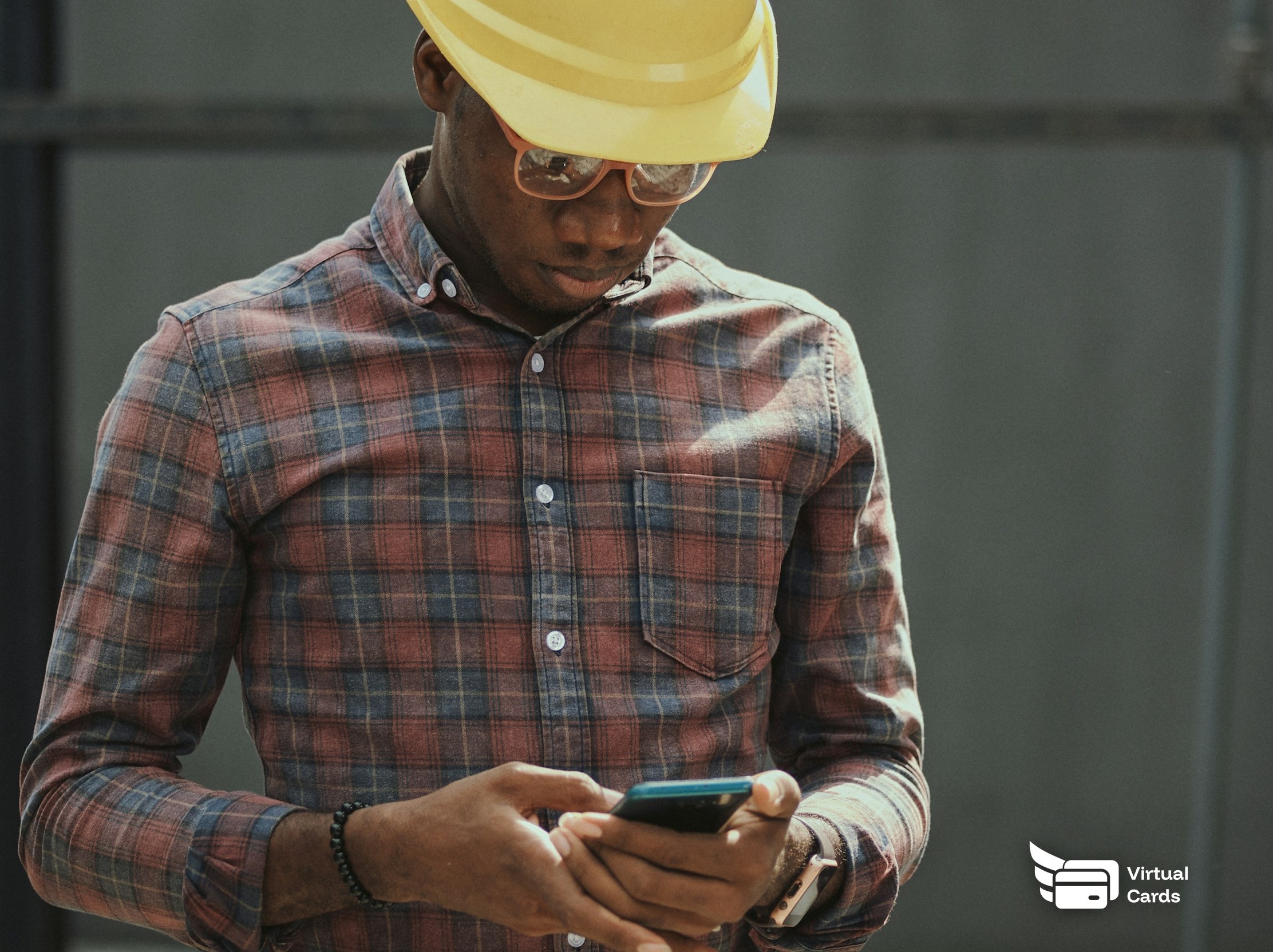 An independent tradesperson in a hard hat checks a card on his phone before buying job materials