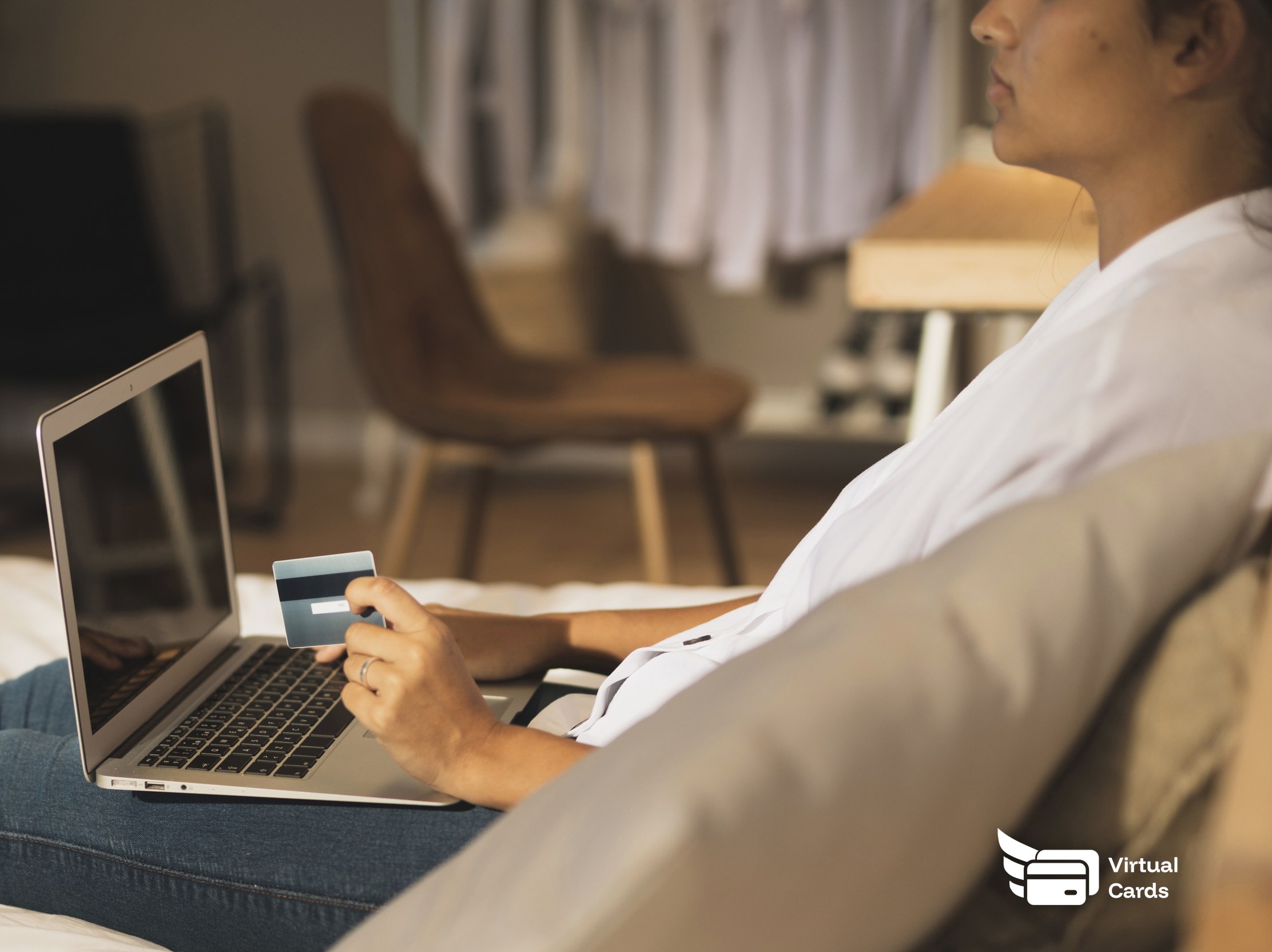 A person's hands near a laptop holding a card while reviewing an online form, representing the choice between a business virtual Visa card and a store gift card.